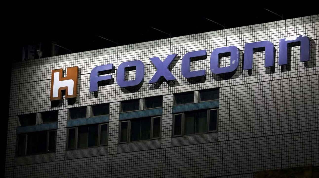 Hoone sein, millel on suur kiri 'Foxconn' ja oranž-valge logo. Sein koosneb valgetest plaatidest, mis on paigutatud ruudumustrisse. Kiri on sinakasvioletne.